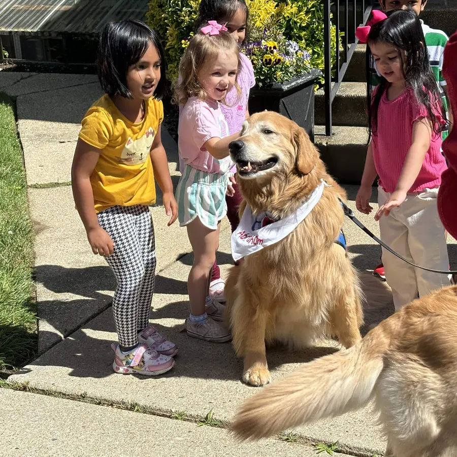 Children greeting a friendly dog during an outdoor visit at Calvary Nursery School