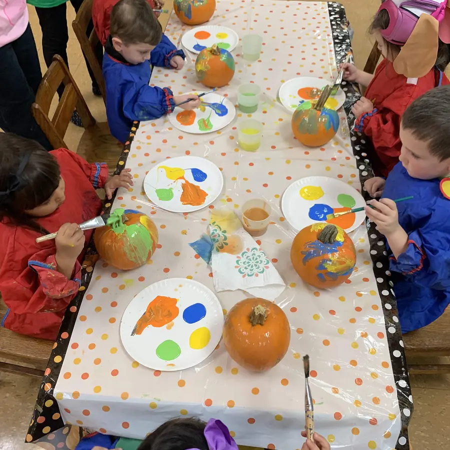 Preschoolers creating seasonal art together at a classroom table